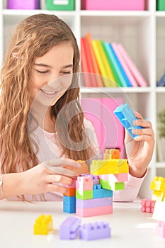 Portrait of curly teen girl playing with colorful plastic blocks