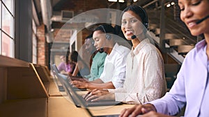 Portrait Of Customer Support Or Telesales Team In Modern Open Plan Office Wearing Headsets