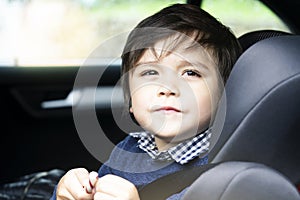 Portrait cut lilttle boy sitting in a car in safety chair, Adorable toddler boy sitting in car seat, Child in car seat with belt o