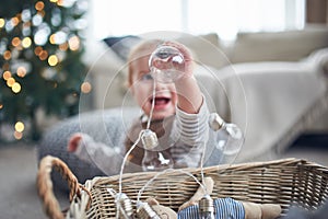 Portrait of a cute 1 year old baby boy sitting on the floor. christmas decorations on a background
