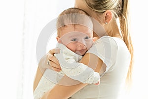 Portrait of cute 3 months old smiling baby boy hugging mother