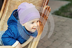 Portrait of cute adorable caucasian baby boy having fun sitting in  wooden rattan rocking chair on house terrace backyard outdoors