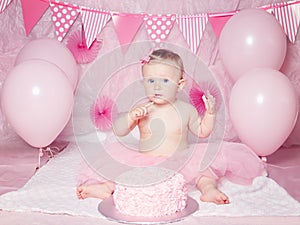 Portrait of cute adorable Caucasian baby girl with blue eyes in pink tutu skirt celebrating her first birthday