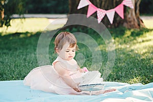 Portrait of cute adorable Caucasian baby girl with dark brown eyes in pink tutu dress celebrating her first birthday