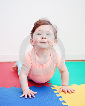 Portrait of cute adorable Caucasian smiling baby boy girl lying on floor in kids room