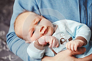 Portrait of cute adorable funny white Caucasian blond little baby boy newborn lying on parent hands