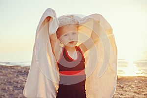 Portrait of cute adorable happy smiling toddler little girl with towel on beach making poses faces having fun