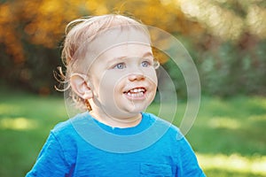 Portrait of cute adorable laughing smiling white Caucasian baby boy child standing among yellow flowers outside