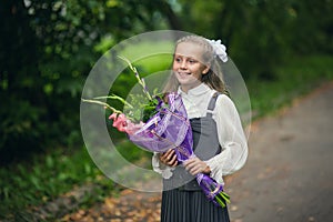 Portrait of cute adorable little caucasian school girl wearing uniform and flowers bouquet going back to school