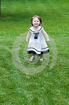 Portrait of a cute adorable little girl child in dress running on grass