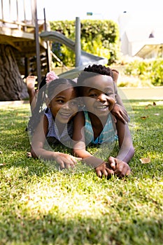 Portrait of cute african american siblings lying on grassy field in park