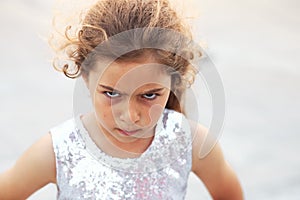 Portrait of cute angry little girl. Kid looking worried  at summer day