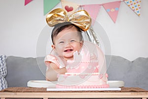 Portrait of cute asian baby girl celebrating her first birthday with pink princess cake