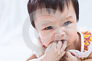 Portrait of cute asian baby girl sucking her fingers in mouth