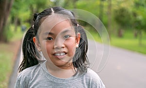 Portrait cute Asian child girl in the park, close up on the smiling face, some sweat drops on the face, gray color t-shirt,
