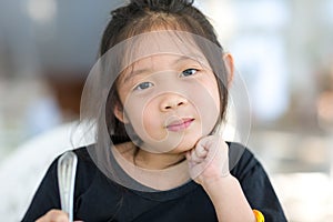 Portrait of Cute Asian Child at Restaurant Holding Spoon