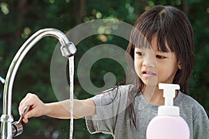 Portrait cute Asian girl aged 4 to 8 years old, washing her hands with soap from the tap. To clean her hands Frequent hand washing