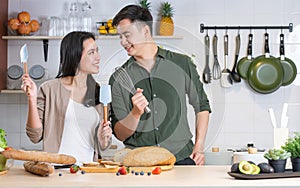 Portrait cute Asian young adult couple lover helping together, cooking in cozy home kitchen in morning, preparing breakfast meal,