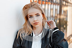 Portrait of a cute attractive young woman with beautiful eyes in a stylish black jacket in a fashionable white shirt