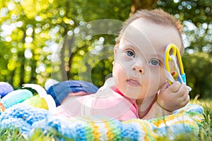 Portrait of Cute baby boy with Down syndrome lying on blanket in summer day on nature