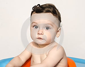 Portrait of a cute baby boy looking at camera sitting in a chair.