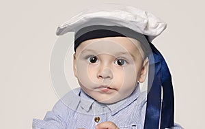 Portrait of a cute baby boy looking at camera wearing a sailor hat.