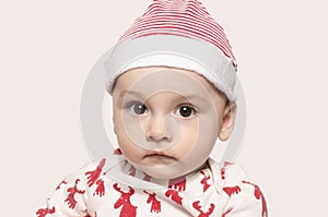 Portrait of a cute baby boy looking at the camera wearing a Santa hat.