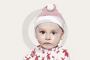 Portrait of a cute baby boy looking at the camera wearing a Santa hat.