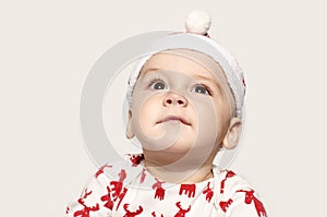 Portrait of a cute baby boy looking up thinking wearing a Santa hat.