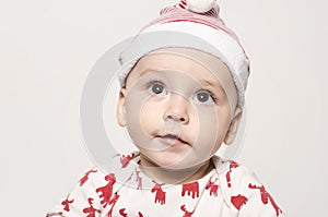 Portrait of a cute baby boy looking up thinking wearing a Santa hat.