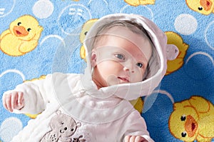 Portrait of a cute baby boy lying in bed on an adorable blanket.