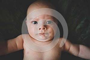 Portrait of cute baby boy makes a funny serious face. Infant frowning.
