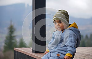 Portrait of a cute baby boy in worm blue overall outdoor with mountain view