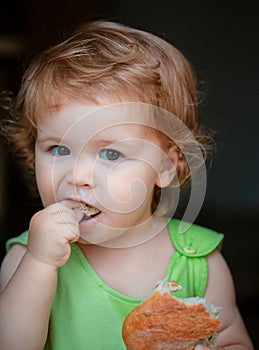 Portrait of cute baby with bread in her hands eating. Cute toddler child eating sandwich, self feeding concept.