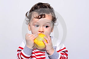 Portrait of a cute baby eating an apple.