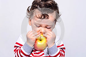 Portrait of a cute baby eating an apple.