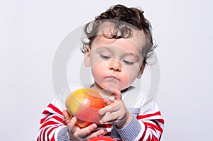 Portrait of a cute baby eating an apple.