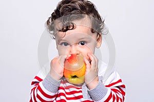 Portrait of a cute baby eating an apple.