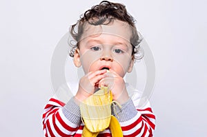 Portrait of a cute baby eating a banana.