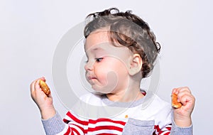 Portrait of a cute baby eating a biscuit.