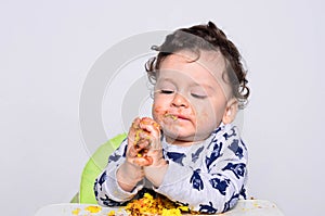 Portrait of a cute baby eating cake making a mess.