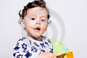 Portrait of a cute baby eating cake making a mess.