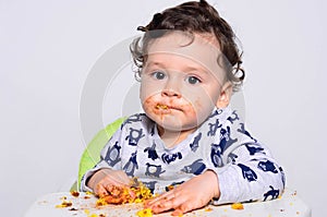 Portrait of a cute baby eating cake making a mess.