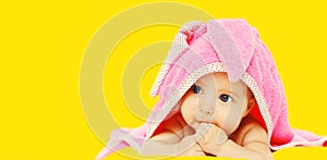 Portrait of cute baby lying under towel on yellow background