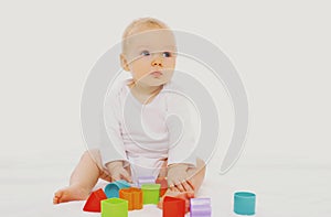 Portrait of cute baby playing on the floor with toys over white background