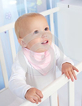 Portrait of a cute baby smiling in white crib
