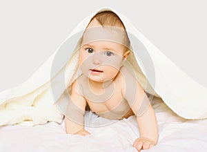 Portrait of cute baby under towel on the bed