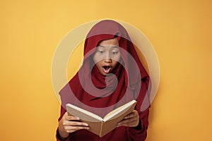 Asian Muslim Teenage Girl Wearing Hijab Shocked and Excited When Reading Book