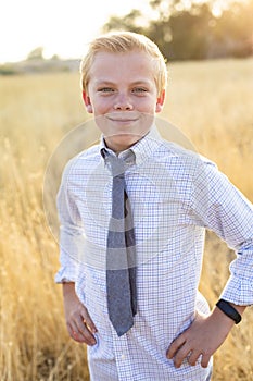 Portrait of cute blond boy standing in a golden grass field