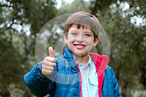 Portrait of a cute blond-haired boy, thumbs up and smile